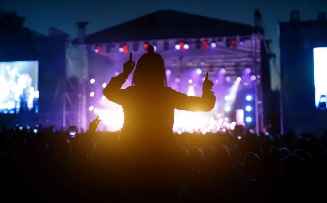 Vrouw zit op iemands schouder tijdens een concert op een festival