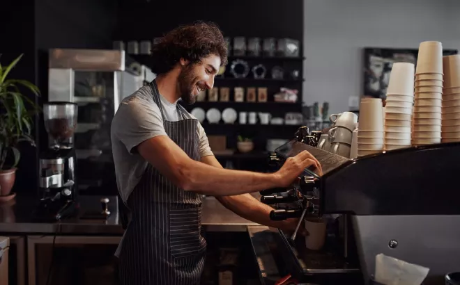 Glimlachende man werkt als barista in een koffiebar