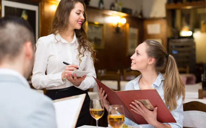 Bijverdiener bedient twee klanten aan tafel op restaurant